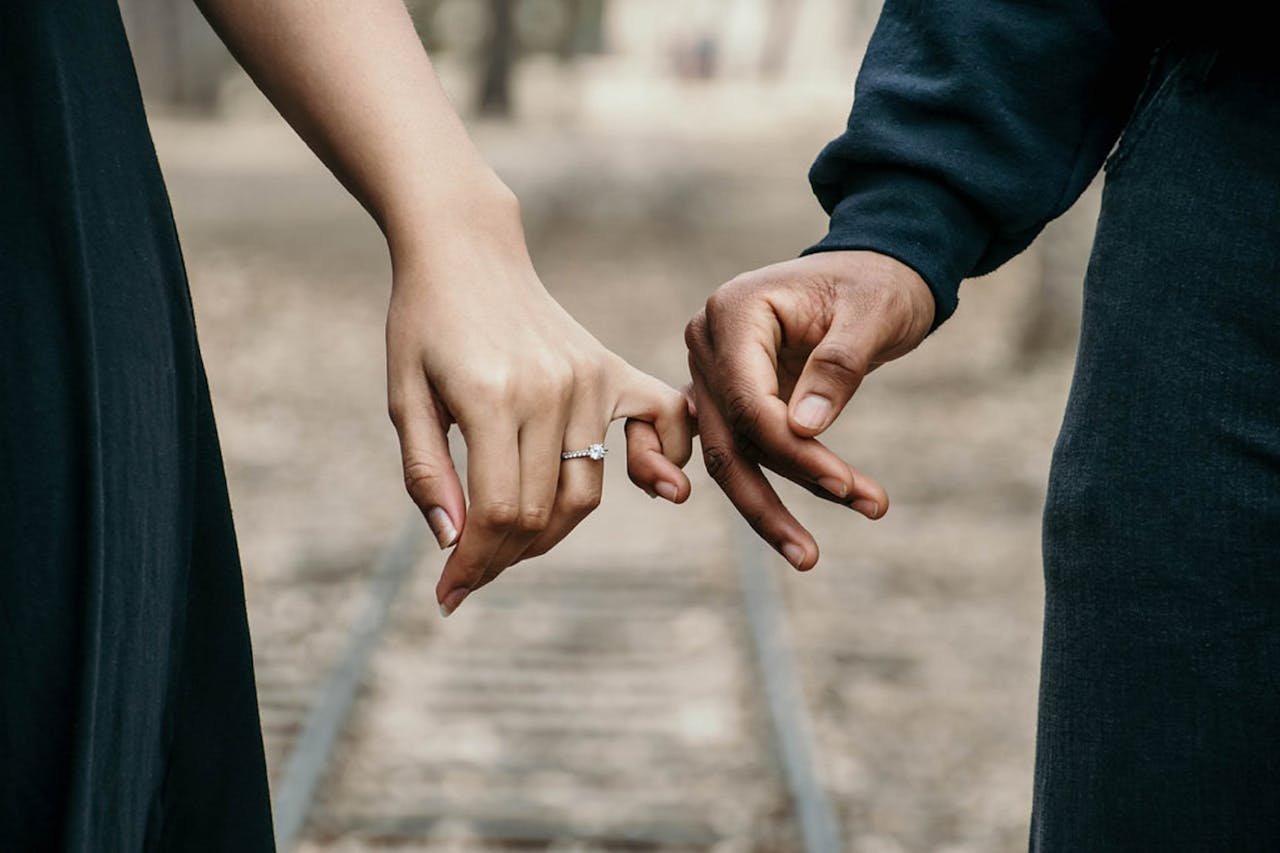 about-me A romantic couple holding hands, symbolizing love and unity on a scenic railtrack.